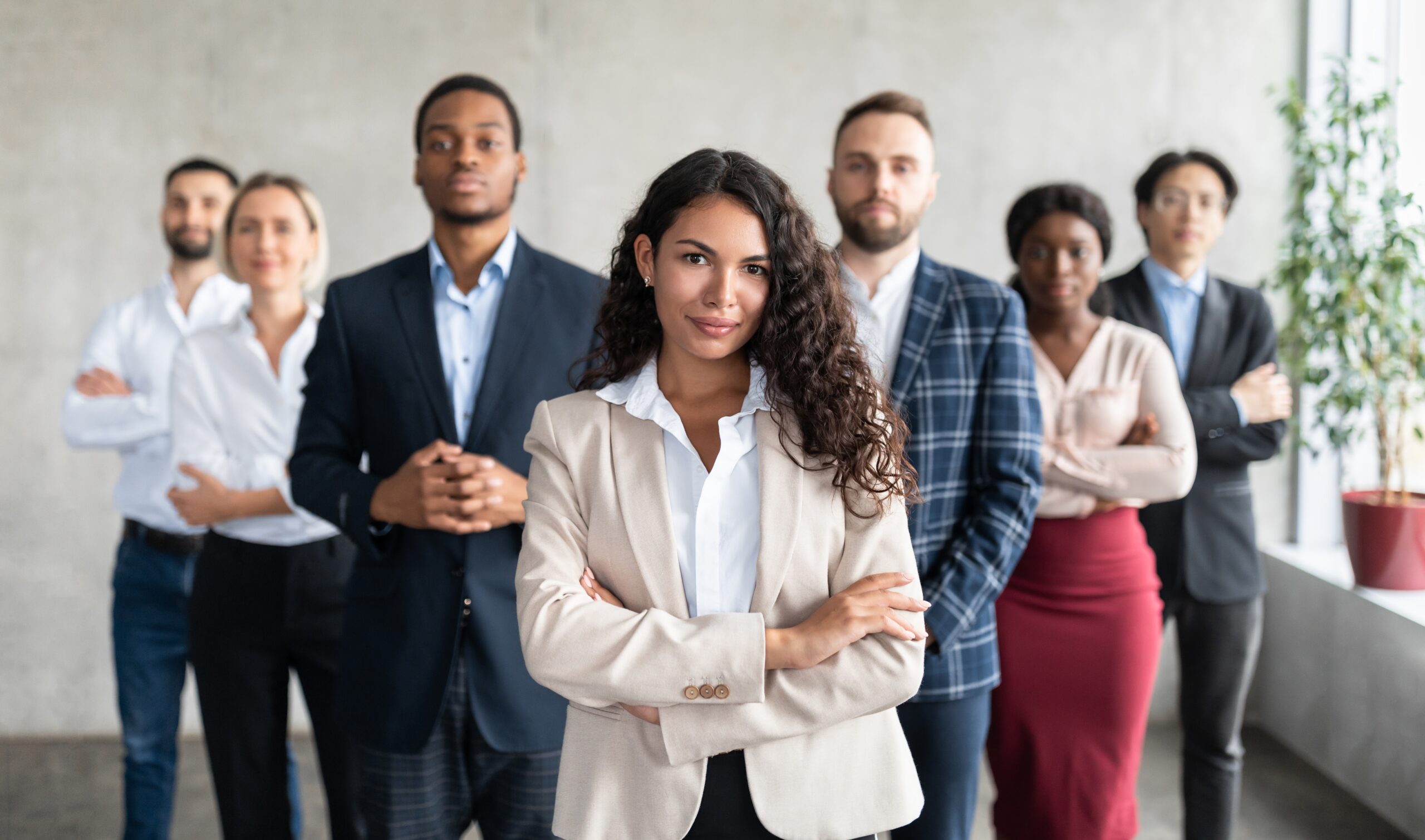 group of business professionals standing led by a woman with arms crossed